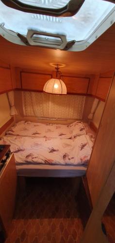 a small bed in a room with a ceiling at Kamp prikolica četvorokrevetna in Crnča