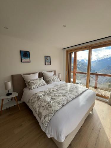 une chambre avec un grand lit et une grande fenêtre dans l'établissement Chalet La Tarine, à Saint-Marcel