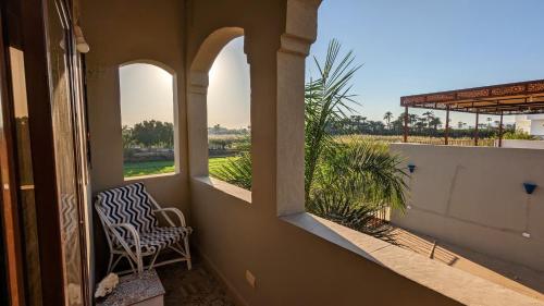 a porch with a chair and a view of a field at Yasmine Guest House in Luxor