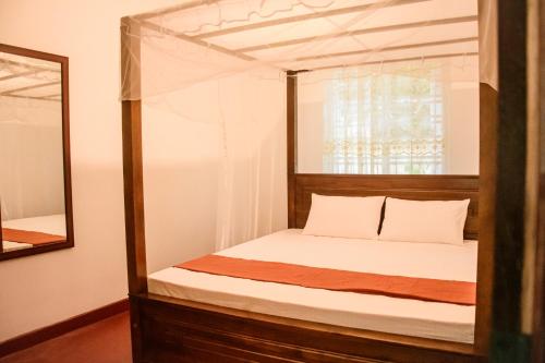 a bedroom with a canopy bed with a mirror at Dien Dee Stays in Hikkaduwa