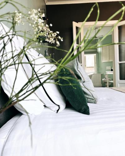 a bed with white pillows and a vase of flowers at Domus Portus in Dendermonde