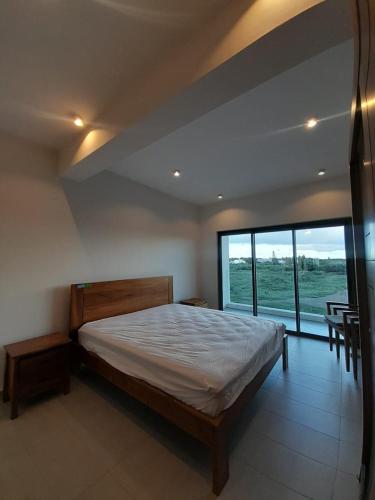 a bedroom with a large bed and a large window at Paille en Queue apartment in Grand Baie