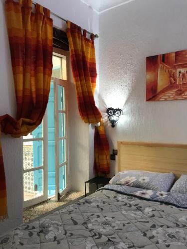 a bedroom with a bed and a large window at Riad chez brahim in Essaouira