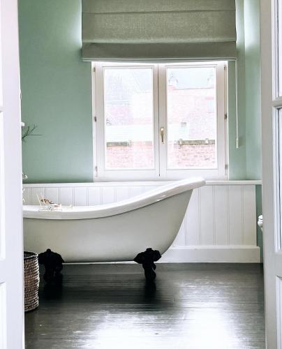 a bath tub in a bathroom with two windows at Domus Portus in Dendermonde