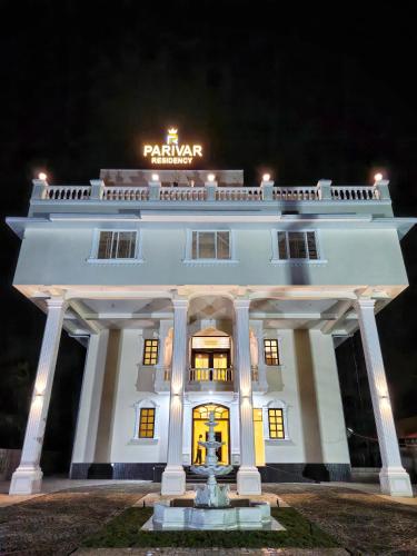 a white building with a fountain in front of it at Parivar Residency in Ullāl