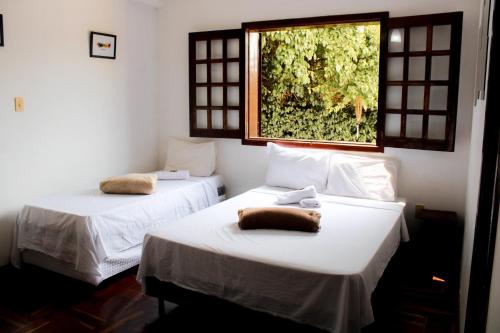 2 camas en una habitación con ventana en Pousada dos Ventos São Lourenço en São Lourenço