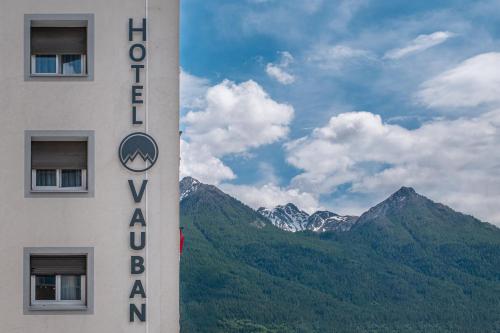 a hotel sign with mountains in the background at Hôtel Vauban Briançon Serre Chevalier in Briançon
