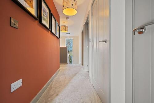 a hallway with an orange wall and a hallway with a hallway at Spacious 4 bed home with gym and tennis court in Lincoln