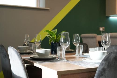 a wooden table with wine glasses and plates on it at Spacious 4 bed home with gym and tennis court in Lincoln