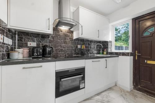 a kitchen with white cabinets and a black oven at 2026 Winner of Travelers Award - Four Bedroom Houses & Studio Apartments - HS2 Contractors - NEC - Birmingham Airport - BCU & Aston University - Heartland Hospital - Jaguar - Star City in Birmingham