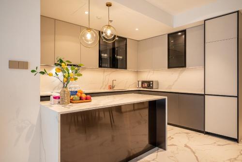 a kitchen with a island with a bowl of fruit on it at Metropole Thu Thiem Condo Apartment in Ho Chi Minh City