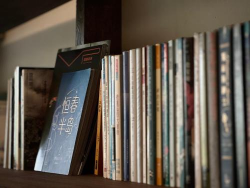 una fila de libros sentados en un estante de libros en 仨食居室, en Hengchun