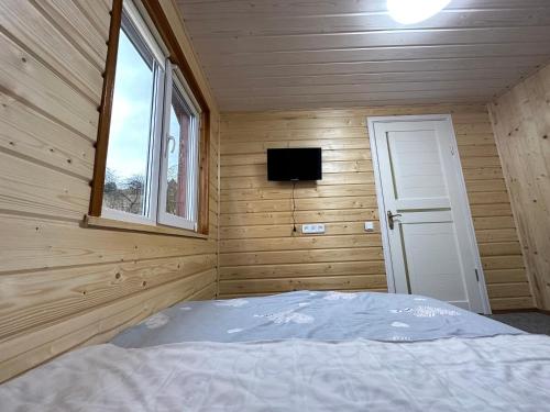 a bedroom with a bed in a wooden room with a window at Карпатська ніч in Plav'ya