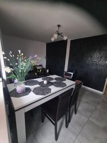 a dining room table with black chairs and a black wall at Apartament Osiedle Centrum 5 in Ustroń