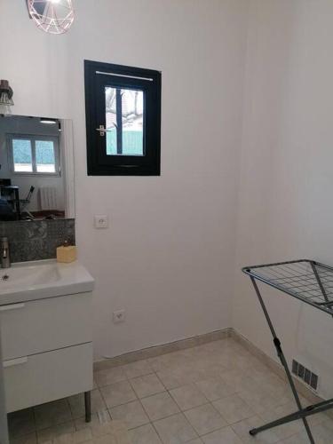 a white bathroom with a sink and a mirror at Maisonnette indépendante in Morangis