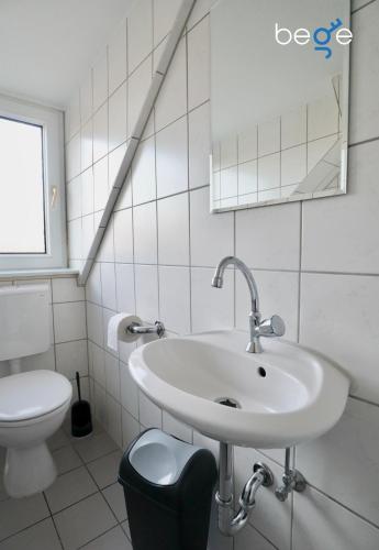a white bathroom with a sink and a toilet at BEGE APARTMENTS Corporate Stay in Gelsenkirchen