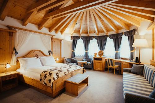 Cette chambre comprend un lit et un bureau. dans l'établissement Hotel Alpenrose, à Arabba