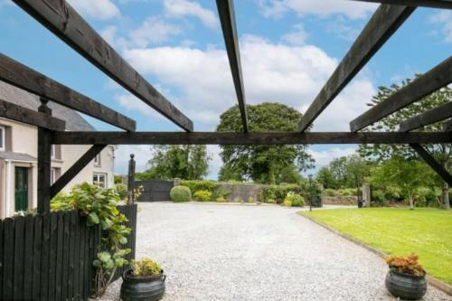 a view from the driveway of a house with a wooden pergola at Sweet Lamb Farmhouse in New Ross