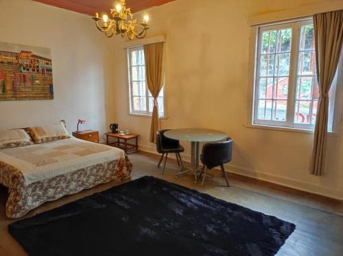 1 dormitorio con cama, mesa y ventanas en Casa Vista Hermosa, en Valparaíso