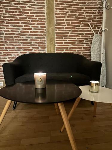 - un canapé noir avec une bougie sur une table basse dans l'établissement Charm’Studio Cosy Suréquipé, à Colombes