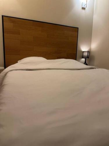 une chambre avec un lit blanc avec une tête de lit en bois dans l'établissement Charm’Studio Cosy Suréquipé, à Colombes