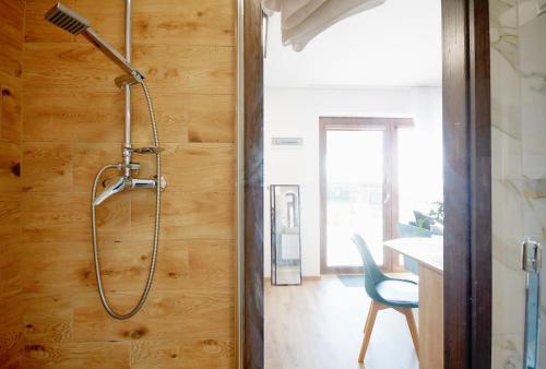 a shower in a bathroom with a wooden wall at Apartments Sunshine - 650 metrów od plaży in Mielenko