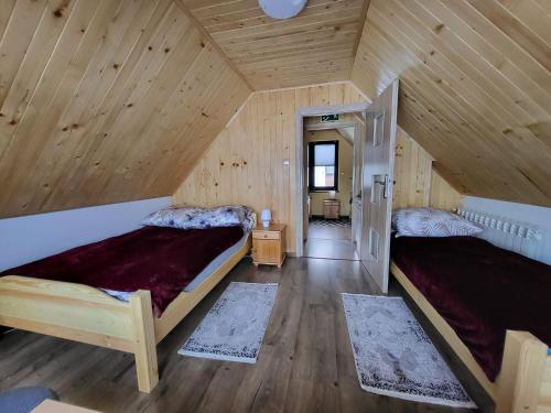 two beds in a room with wooden walls at Domek Bieszczadzki Staw - Noclegi Czarna in Czarna