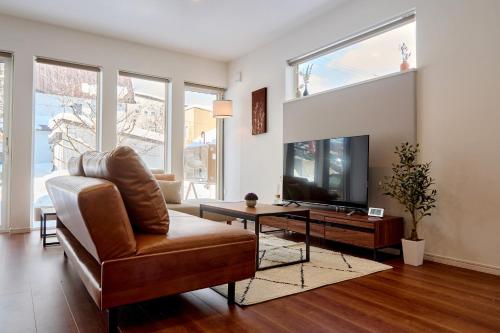 a living room with a couch and a television at KOYO・YUKI in Furano