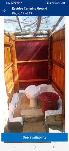 ein Bad mit einem WC und einer roten Wand in der Unterkunft Camping Ground @ Eastdee Lidlidda in Lidlidda