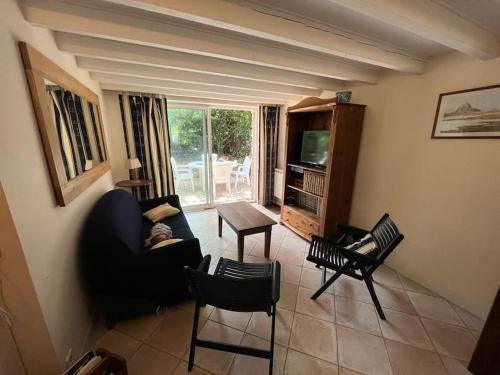 un salon avec un canapé, des chaises et une télévision dans l'établissement Maison à 100 m de la plage et proche du centre, à Jullouville