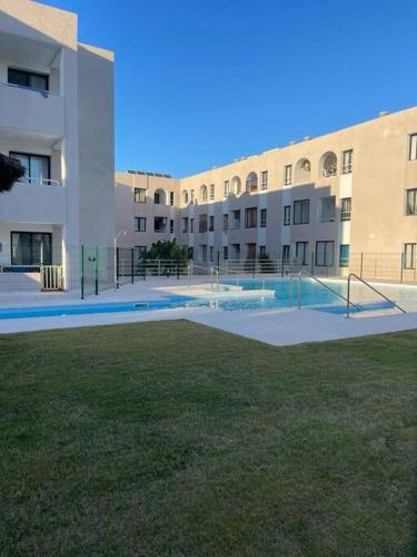 a large building with a tennis court in front of it at Apartamento Verde en Sotogrande in Sotogrande
