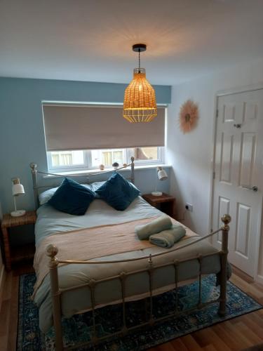 a bedroom with a bed with blue walls and a chandelier at Laurel Apartment in Bourton on the Water