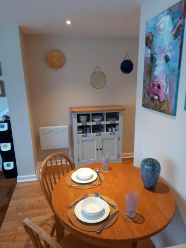 a dining room with a wooden table with plates on it at Laurel Apartment in Bourton on the Water