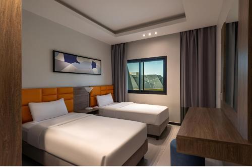 una camera d'albergo con due letti e una scrivania di HDB Al Khobar Resort & Spa a Al Khobar