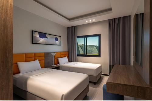 a hotel room with two beds and a desk at HDB Al Khobar Resort & Spa in Al Khobar
