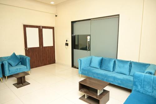 a living room with a blue couch and two chairs at HMR Hotels - Hotel HMR Royal Inn in Pune