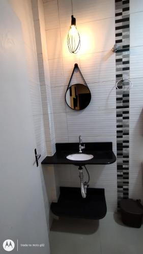 y baño con lavabo y espejo. en Quitinete compacta, en Balneário Camboriú