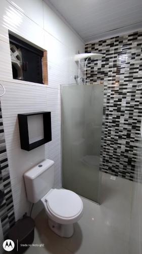 a bathroom with a toilet and a glass shower at Quitinete compacta in Balneário Camboriú