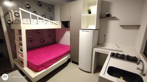 um pequeno quarto com um beliche e uma cozinha em Quitinete compacta em Balneário Camboriú