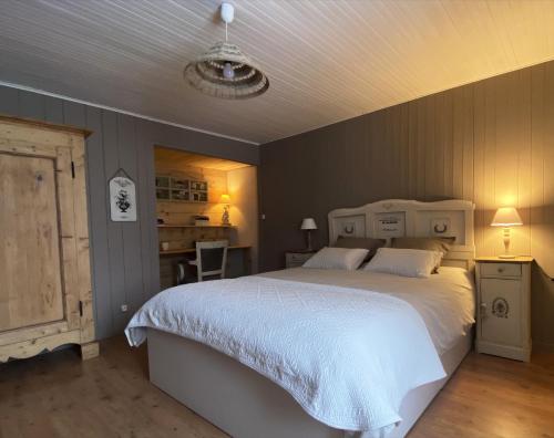 a bedroom with a large white bed and a desk at La ferme d'Auguste in Thorens-Glières