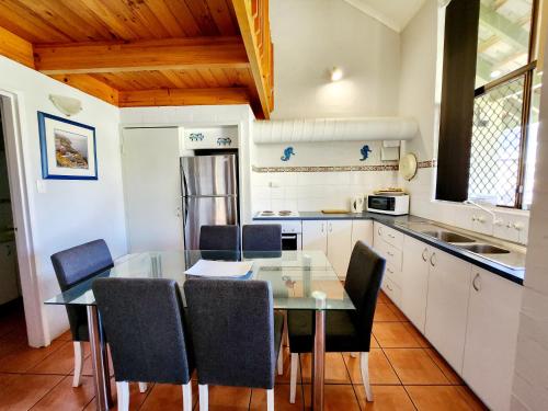 a kitchen with a glass table and chairs at Just Beachy Loft Villa in Mandurah