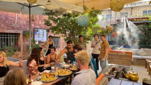 a group of people sitting around a table eating food at Carob Hostel in Amman