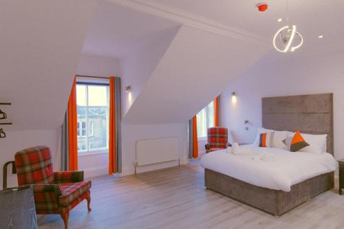- une chambre avec un lit et deux chaises dans l'établissement Mayfield Suites, à Édimbourg