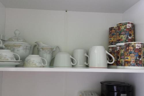 a shelf with cups and other dishes on it at Dom Pedro 26 in Guarujá