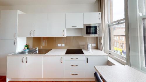 a kitchen with white cabinets and a sink and a window at Flat 302 Centre Nottingham in Nottingham