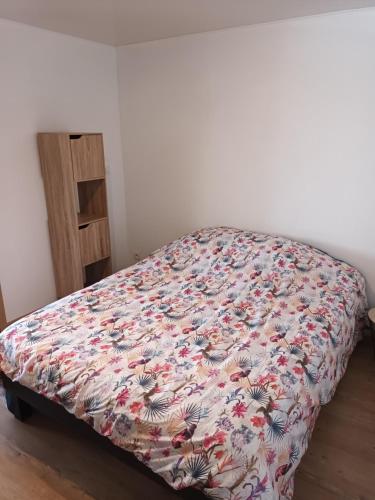 un letto in una camera da letto con copriletto floreale di Appart de charme au bord de l'eau 