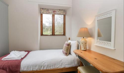 a bedroom with a bed and a desk and a window at Scandale Cottage in Ambleside