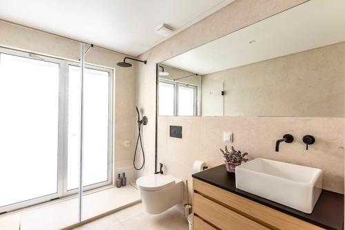 uma casa de banho com um lavatório, um WC e um espelho. em New! Superb & Bright Apartment in Lisbon em Lisboa