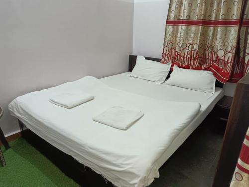 Cama en habitación con sábanas y almohadas blancas en The Royal Lake View Villa, en Udaipur