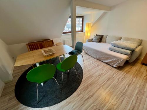 a living room with a table and green chairs at Hinterhaus Apartments in Leipzig